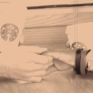 Two people holding hands over a cup of coffee.