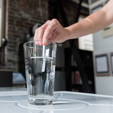 A Drinkably water test strip being dunked in a glass of water.