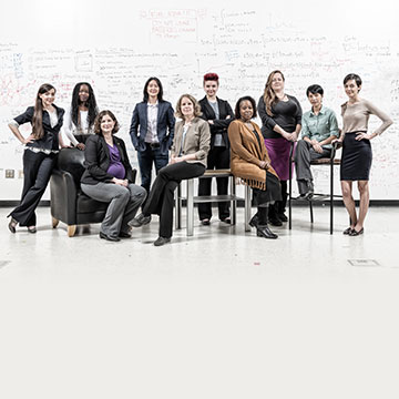 photo - group of 10 women sitting and standing in front of large white board covered with notes