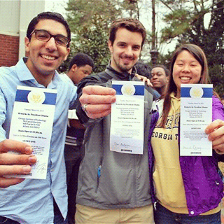 Three students hold up their tickets to see President Obama speak at Georgia Tech.