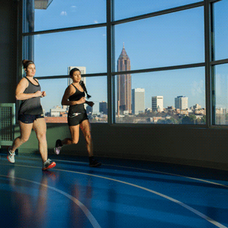 Two young women jog around the indoor track at the top of the Georgia Tech Campus Recreation Center.