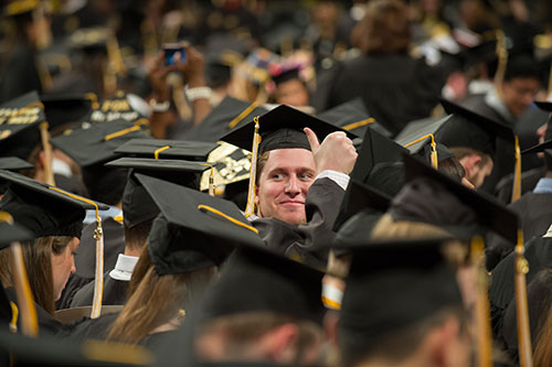 A graduate gives the thumbs-up sign to onlookers at the December Commencement Ceremony.