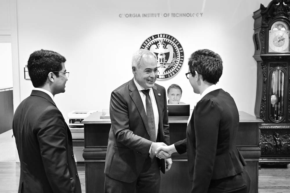 President Cabrera shaking hands with two students in the foyer of the Carnegie building