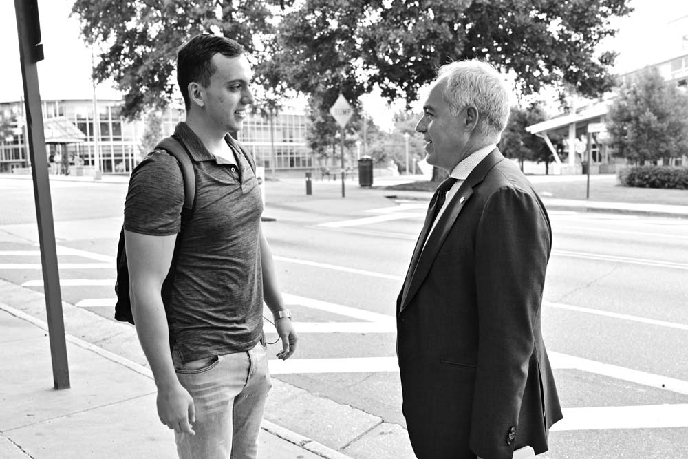 Student in a t-shirt talking to President Cabrera on the street