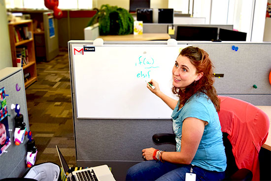 Subject sitting in office cubicle writing programming language on whiteboard