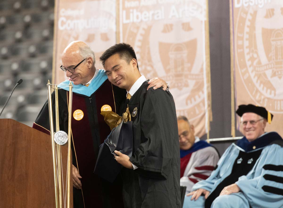 Provost Bras with his arm around a student on stage at an event