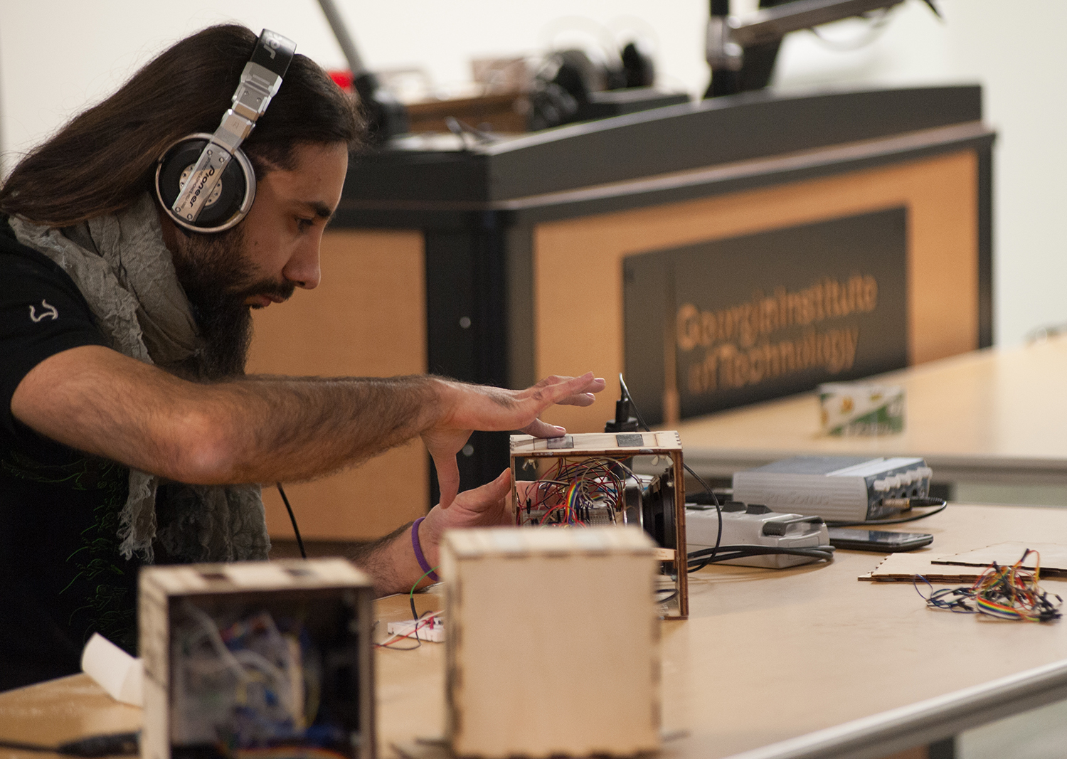 Man wearing headphones pressing a button on a small wooden box
