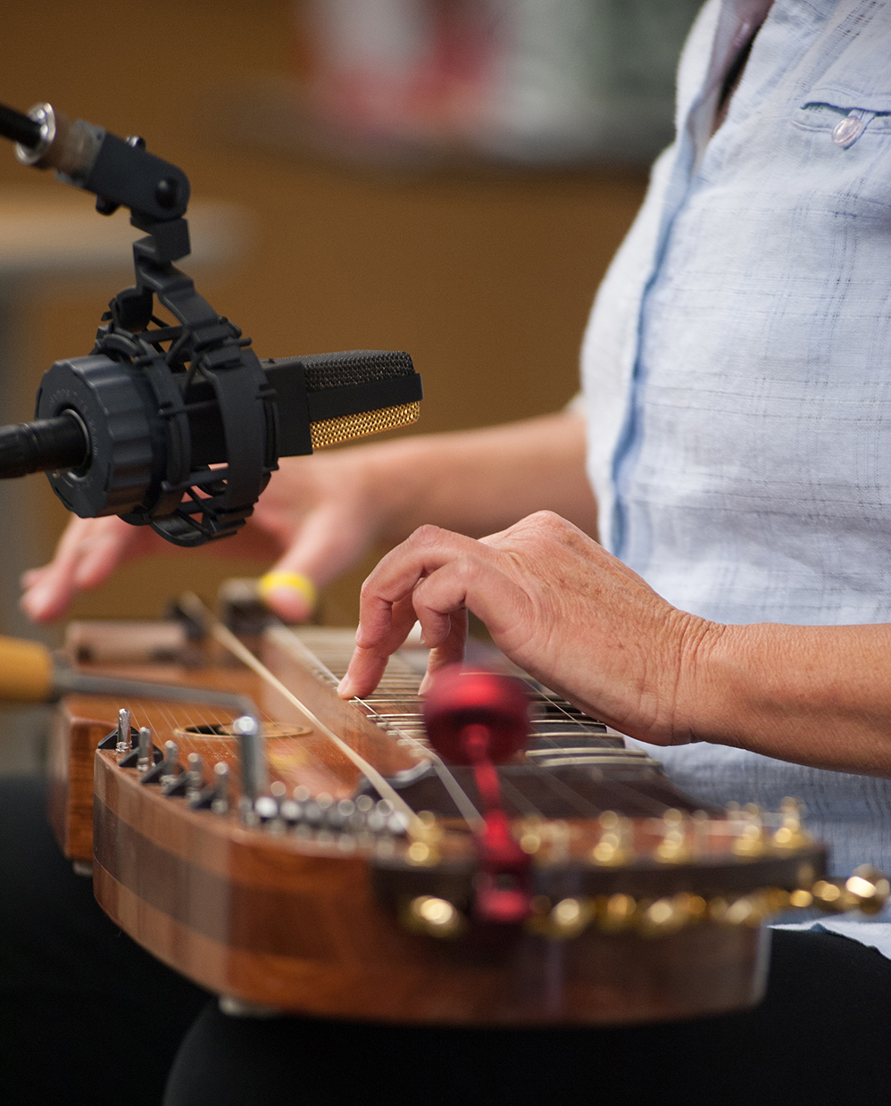 Woman's hands playing a stringed instrument that is held horizontally in the lap