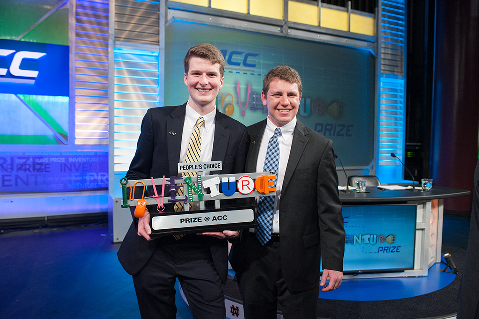 Two inventors on stage at the ACC Inventure Prize ceremony holding a trophy for the People's Choice award.