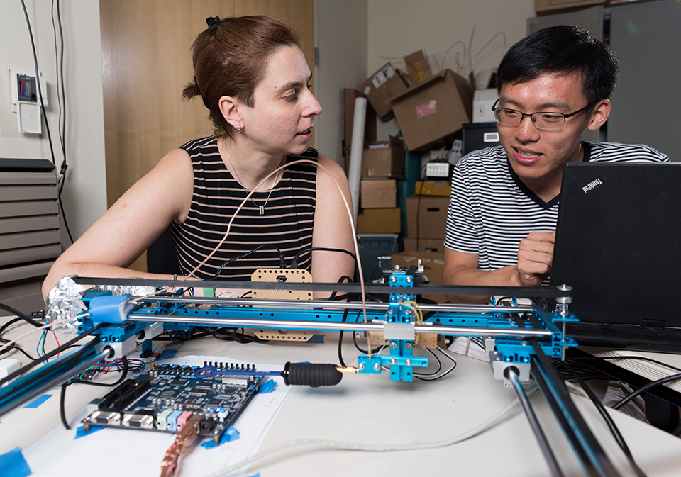 Georgia Tech Assistant Professor Alenka Zajic and graduate student Derrick Chu discuss a device used to systematically measure side-channel outputs from electronic devices