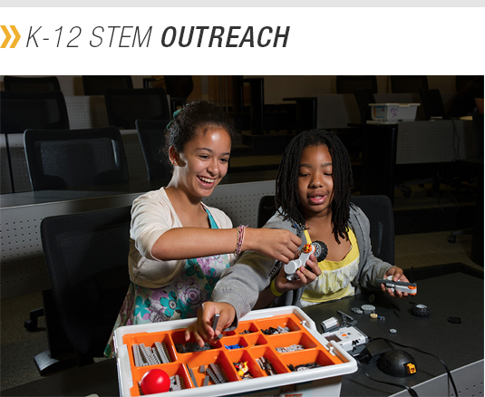 K-12 STEM Outreach (photo shows a college student helping a child build something out of a selection of parts.