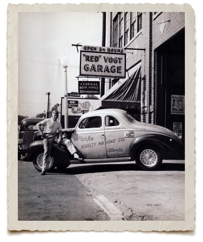 Red Vogt leaning against a Parks Ford outside his mechanic shop