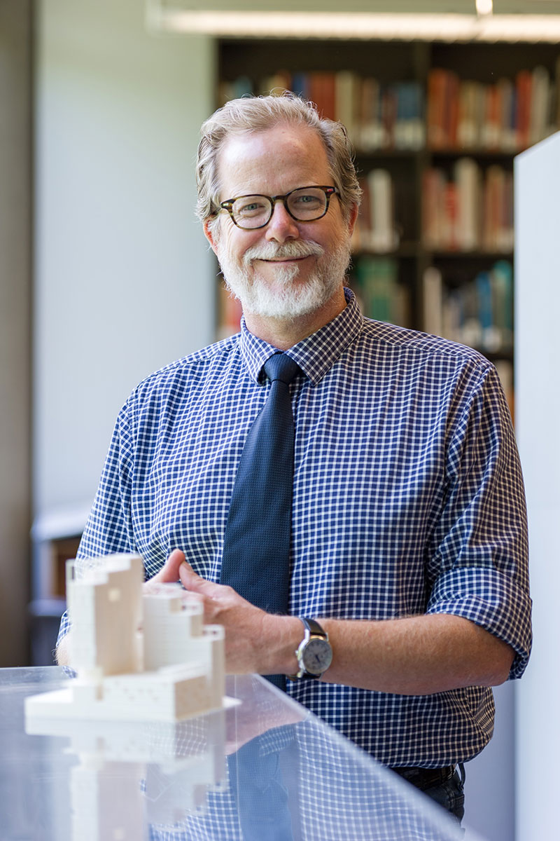 Portrait of Michael Gamble standing in front of a small maquette of a building