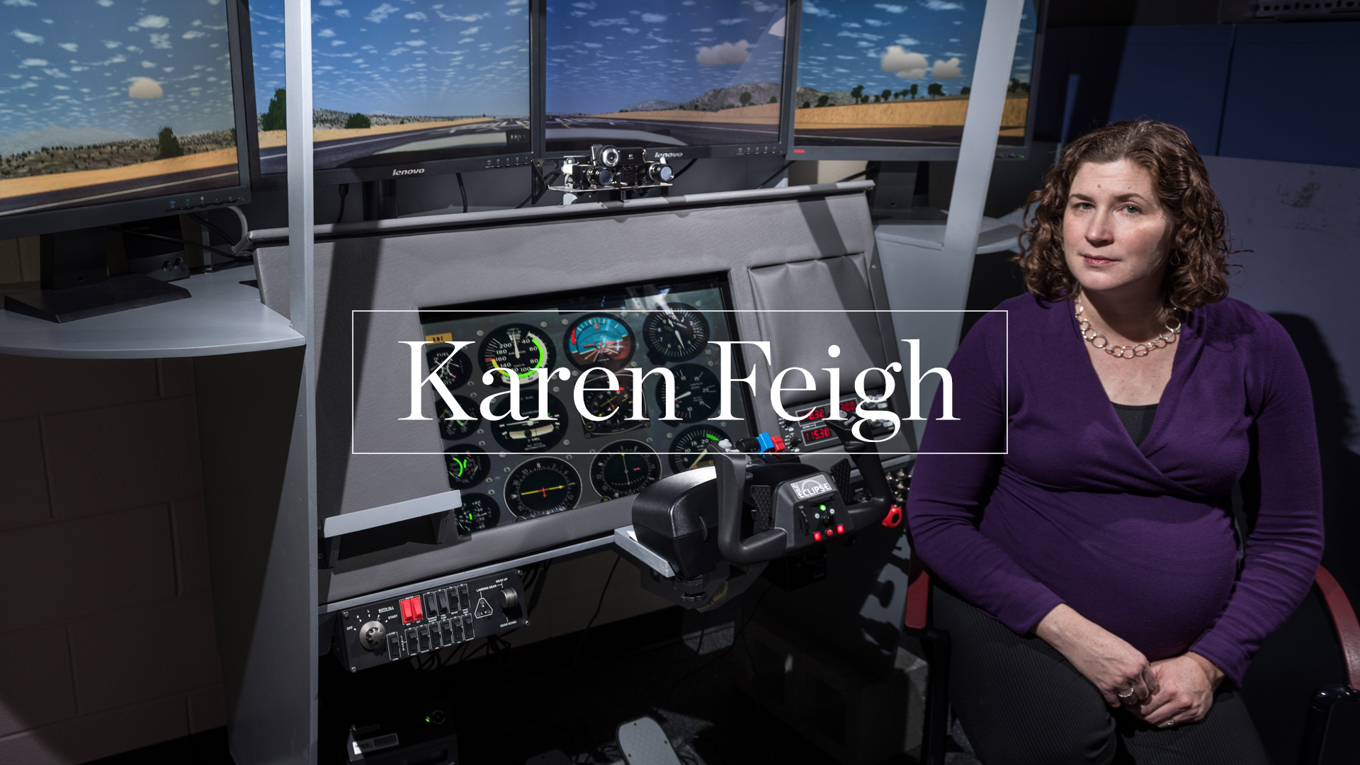 photo -  Karen Feigh sitting next to flight simulator controls