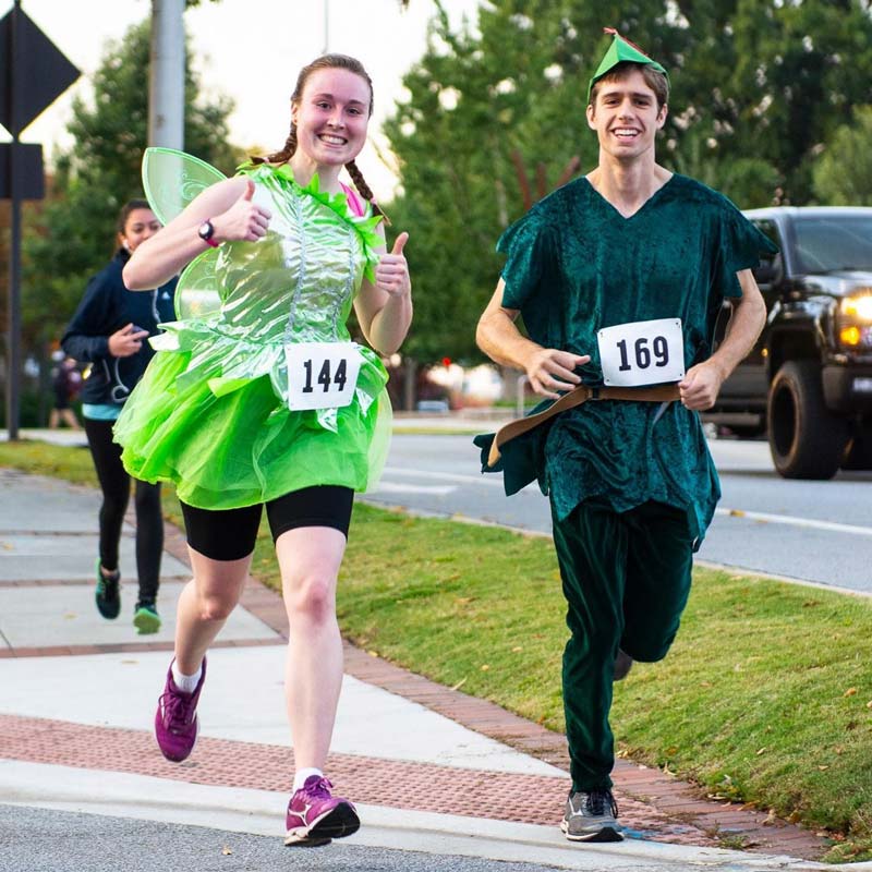 A woman and a man in costumes running a race