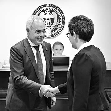 President Cabrera shaking hands with a student in front of the seal of the Georgia Institute of Technology
