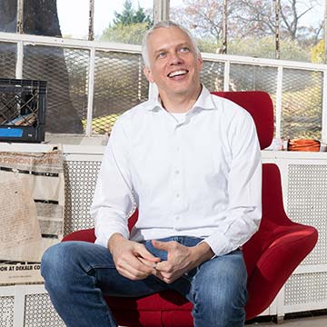 Ryan Gravel sitting in a stylish chair, smiling and looking up