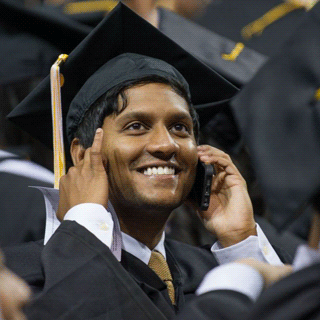 A graduate on his cell phone during the Commencement ceremony