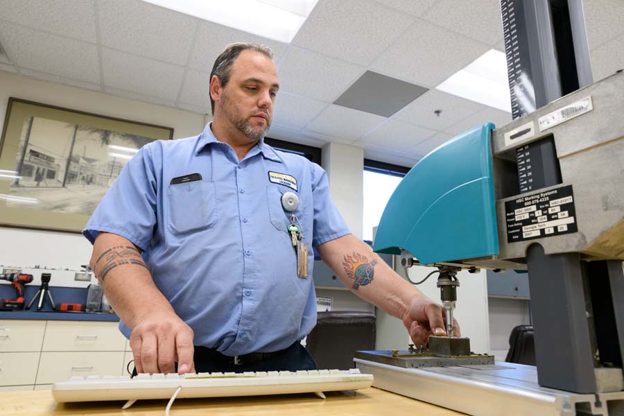 Locksmith Jason Heib is electronically stamping a key with a code and a sequential number.