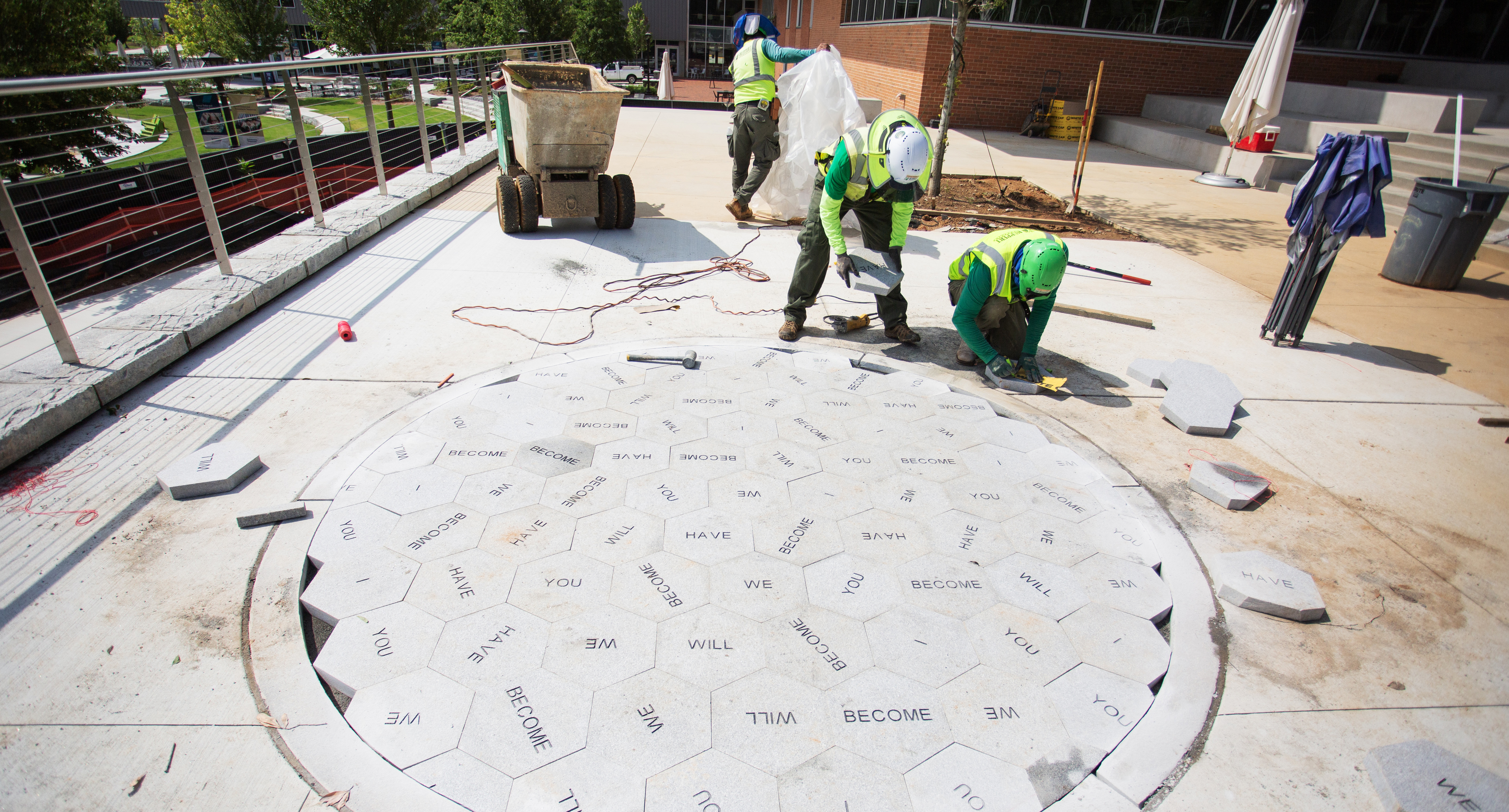 Construction progress of outdoor installation with stone hexagons in a circular pattern.