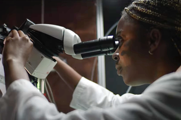 biomedical student looking through microscope