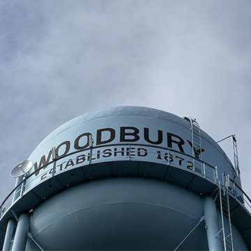 Woodbury text on a watertower with blue sky and clouds.