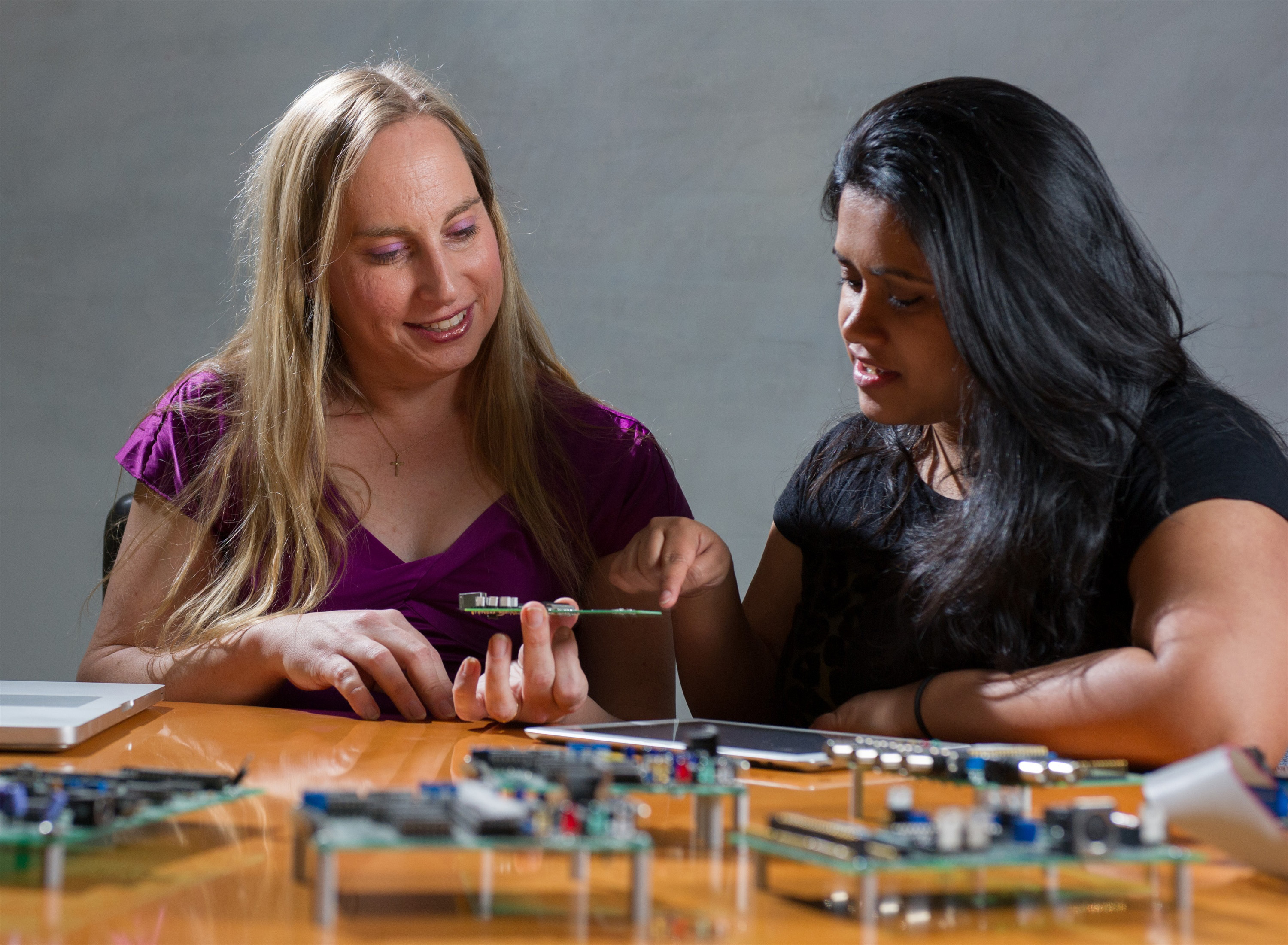 Professor Jennifer Hasler (left) and graduate student Suma George examine a field programmable analog array (FPAA) board that includes an integrated circuit with biological-based neuron structures for power-efficient calculation. Hasler’s research indicates that this type of board, which is programmable but has low power requirements, could play an important role in advancing neuromorphic computing. (Georgia Tech Photo: Rob Felt)