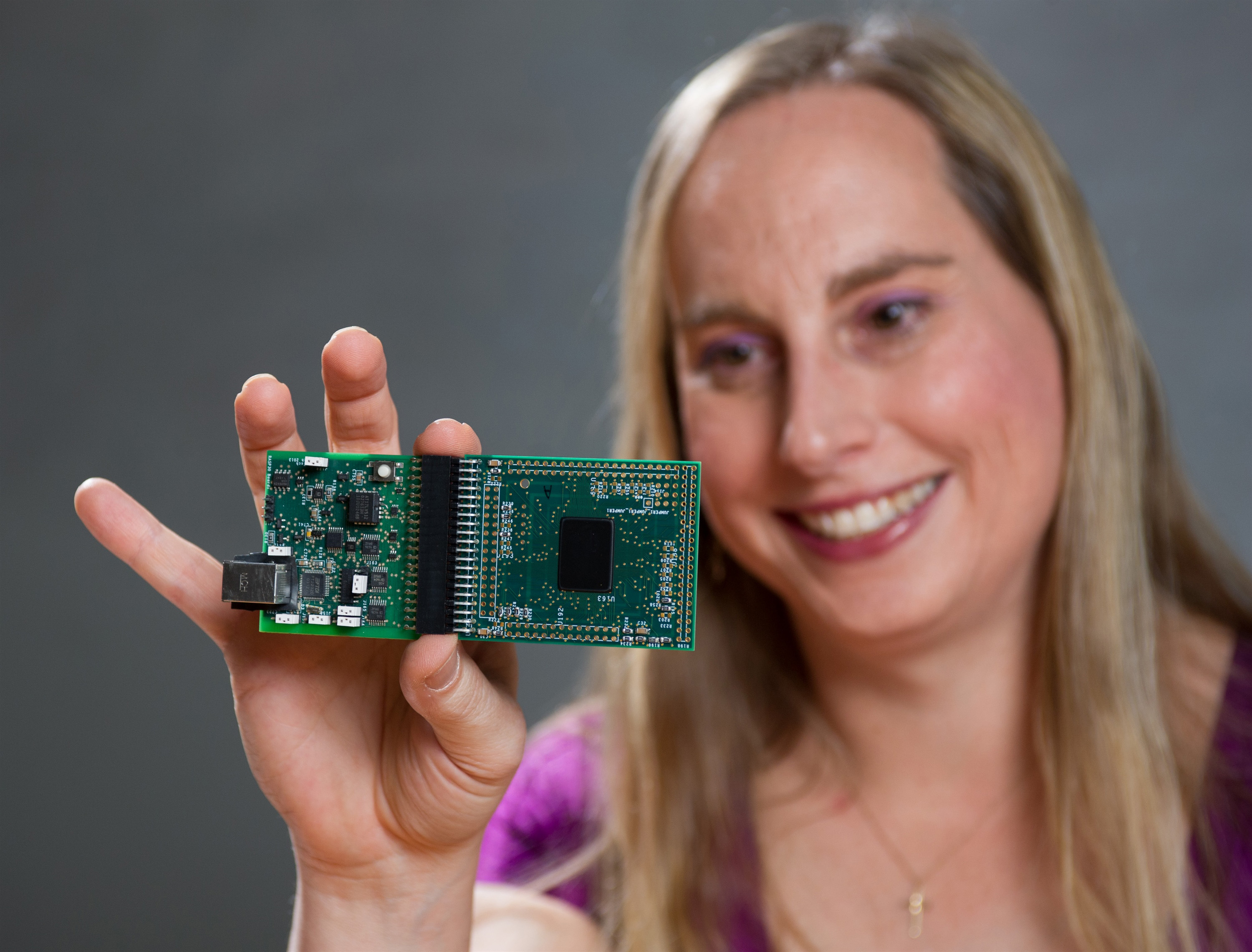 Professor Jennifer Hasler displays a field programmable analog array (FPAA) board that includes an integrated circuit with biological-based neuron structures for power-efficient calculation.  Hasler’s research indicates that this type of board, which is programmable but has low power requirements, could play an important role in advancing neuromorphic computing. (Georgia Tech Photo: Rob Felt)