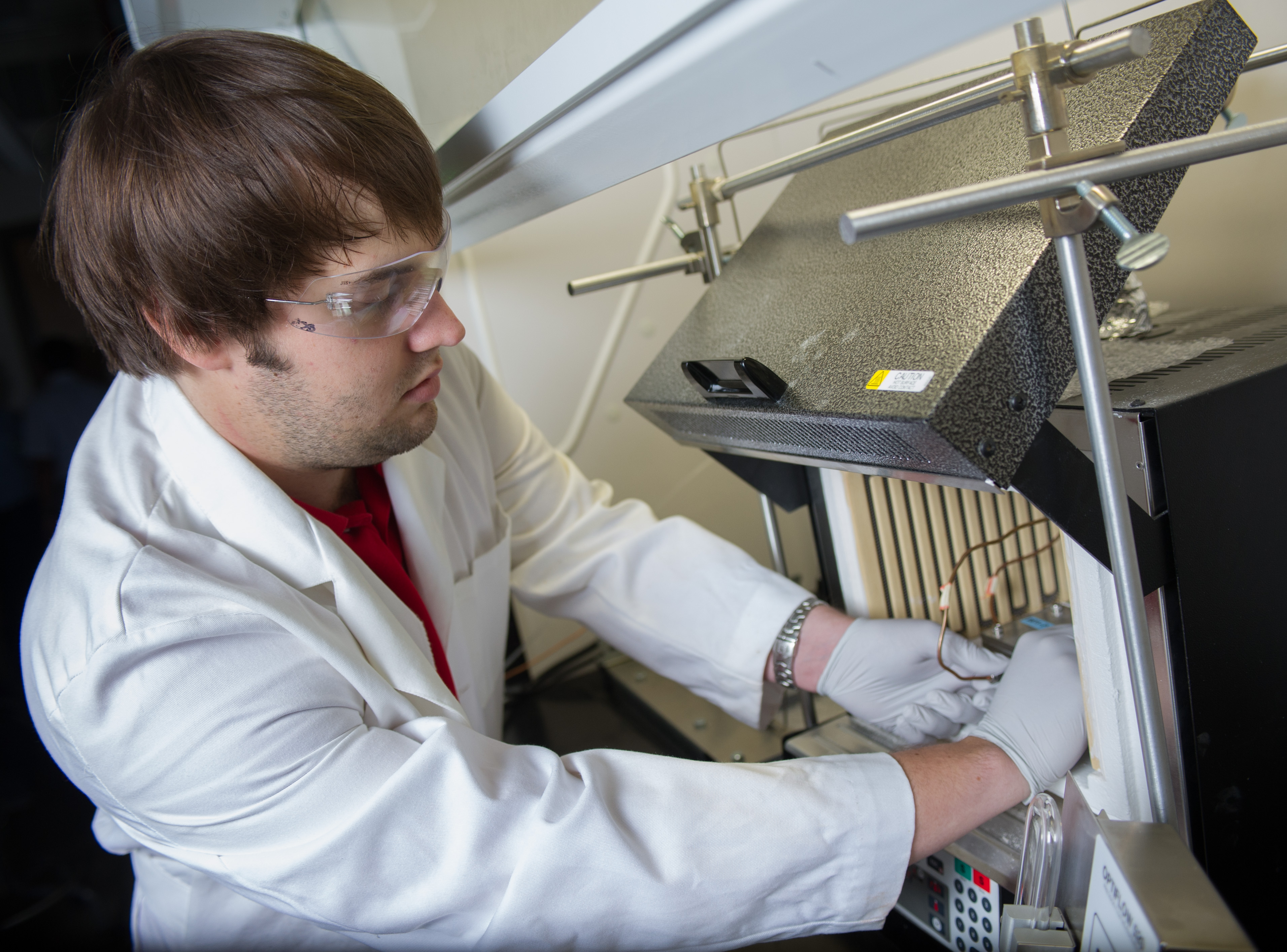 Georgia Tech researcher Andrew Brown places a finished hollow fiber metal-organic framework (MOF) membrane module into a membrane testing apparatus to measure its gas separation properties. (Credit: Rob Felt)