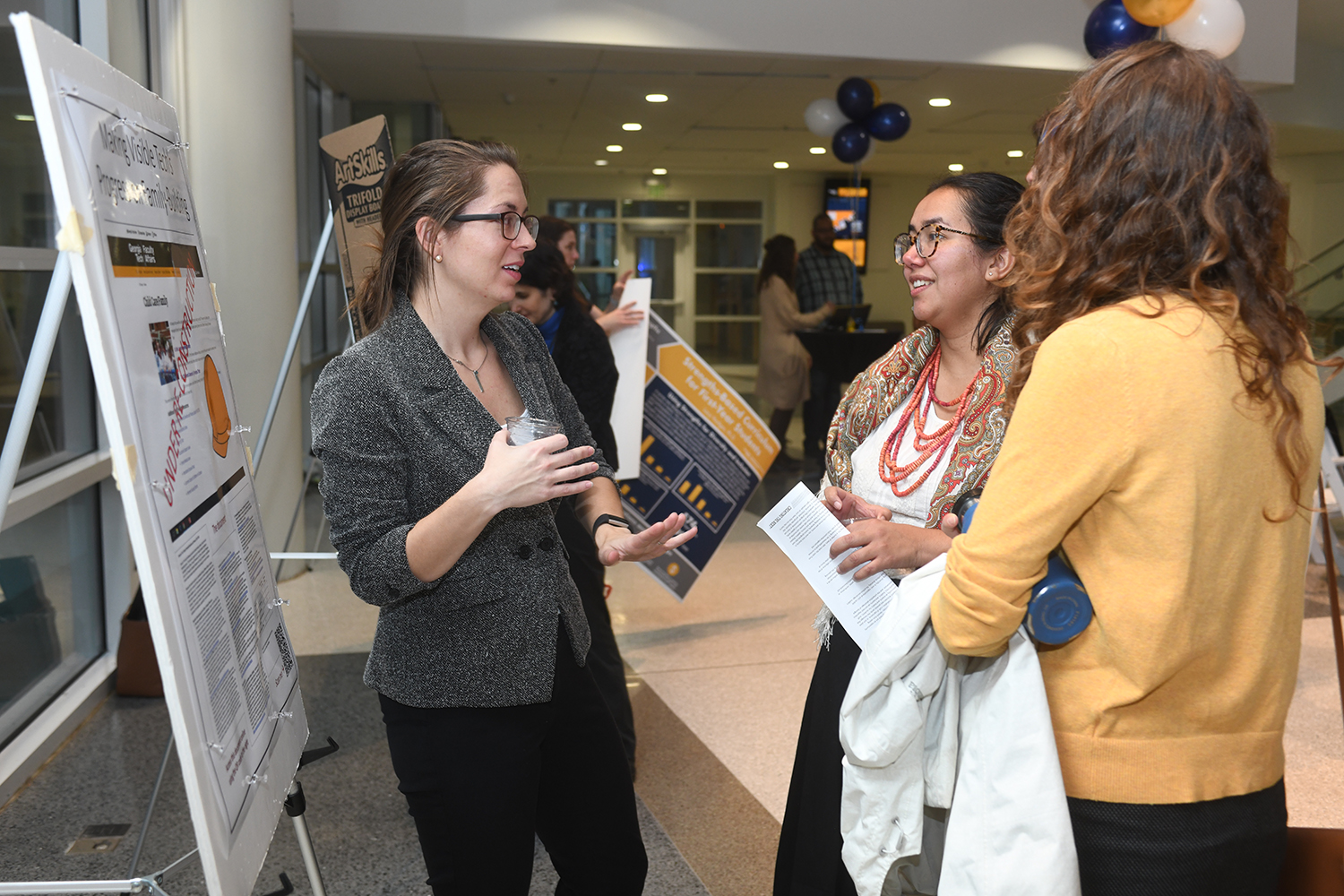 Emily Weigel (left), academic professional in the School of Biological Sciences, talks with attendees about her work at the Diversity and Inclusion Fellows Program Poster Expo on Nov. 13.
