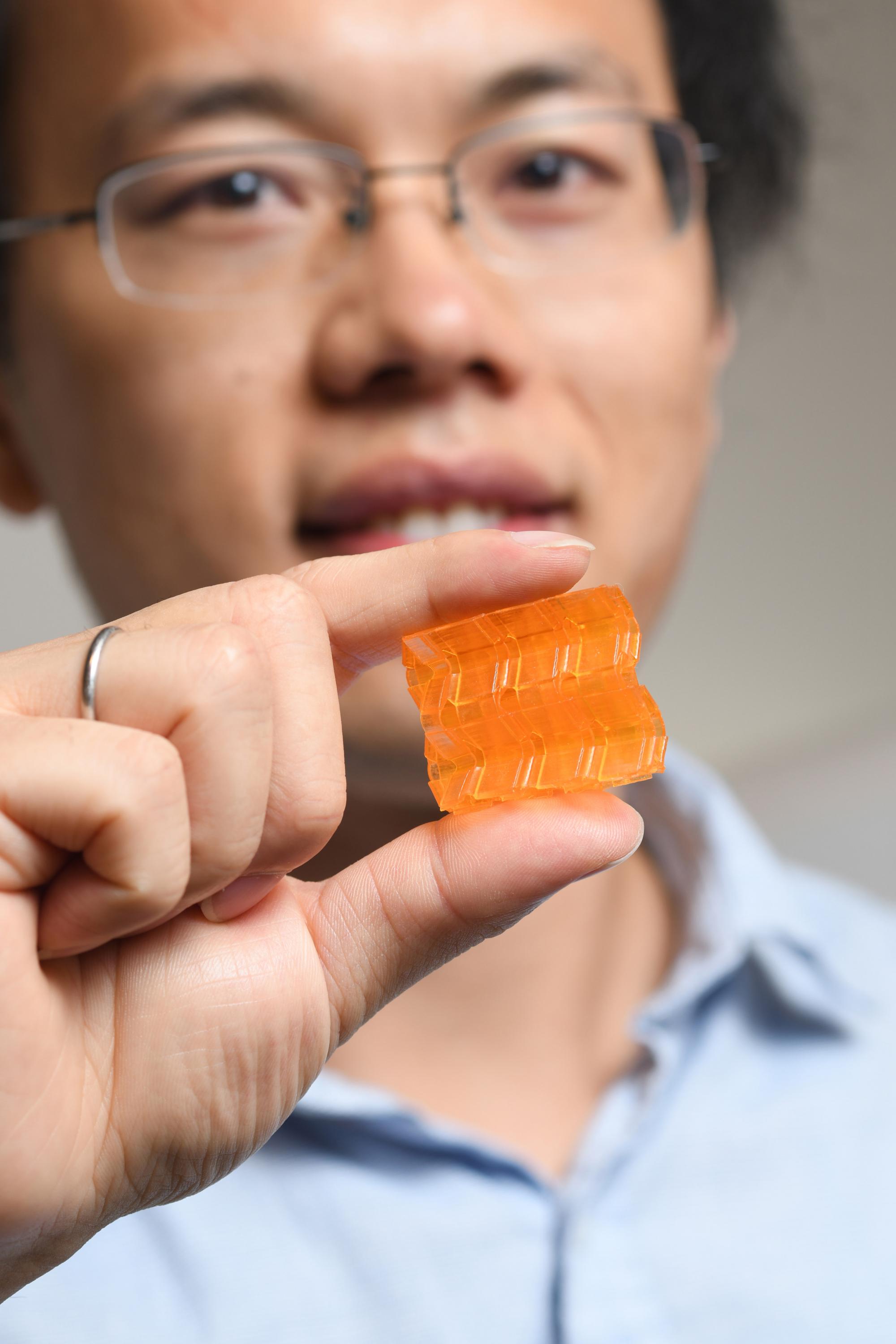 Georgia Tech postdoctoral fellow Xiao Kuang demonstrates the compressibility of origami structures created through Digital Light Processing 3D printing. (Credit: Christopher Moore, Georgia Tech).