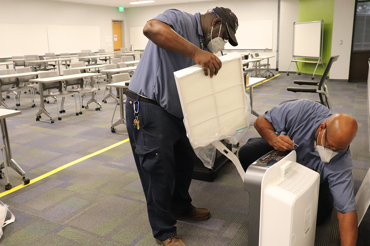 Kenneth Osborne (Maintenance Worker I) and Gerry Green (Maintenance Worker I) install an air scrubber in a classroom space on Tuesday, Aug. 17. (Photo by Jeff Wiley)