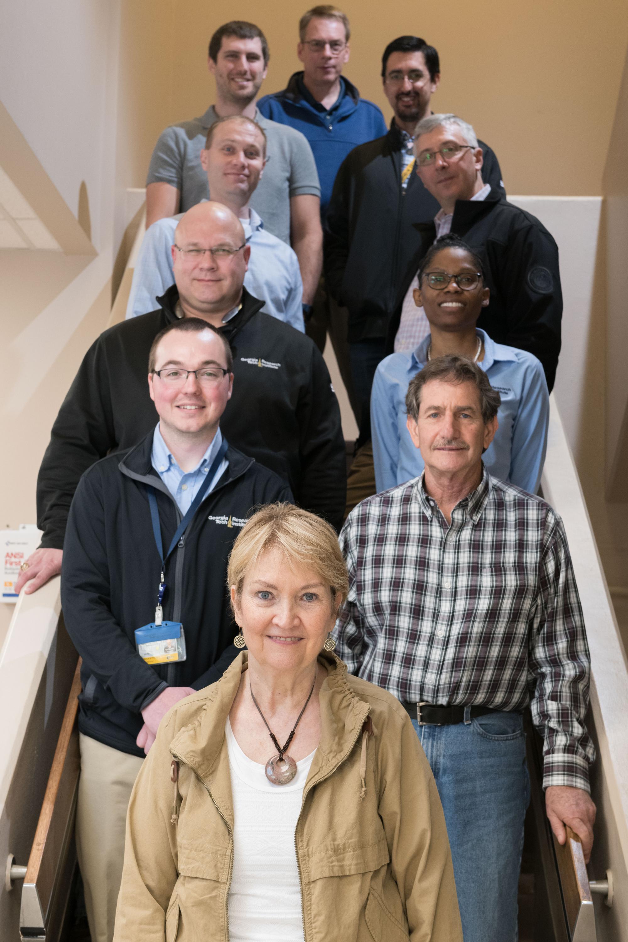 Photo shows a portion of the Atlanta-based GTRI team that is supporting the Air Force Distributed Common Ground System. Shown (foreground to the top, left-to-right) are Molly Gary, Joshua Phillips, Alan Nussbaum, Kyle L. Davis, Jacqueline Fairley, Collin Brown, Lou Tirino, Ryan Simko, Nathan Adams and Jeff Smart. (Photo Credit: Allison Carter, Georgia Tech)