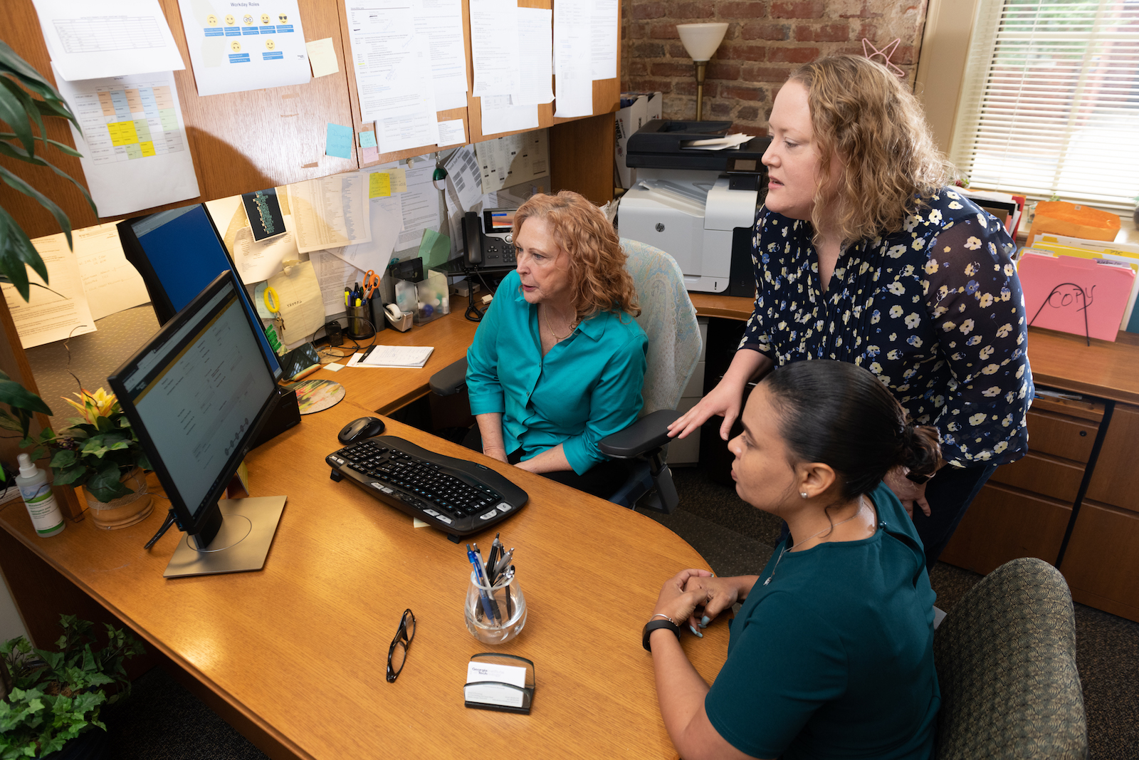 Erin Nagle (standing), faculty affairs administrative manager for the College of Sciences, talks with Leslie Dionne White (left), administrative manager of the School of Psychology, and Kristie Clark, assistant to the chair of the School of Psychology.