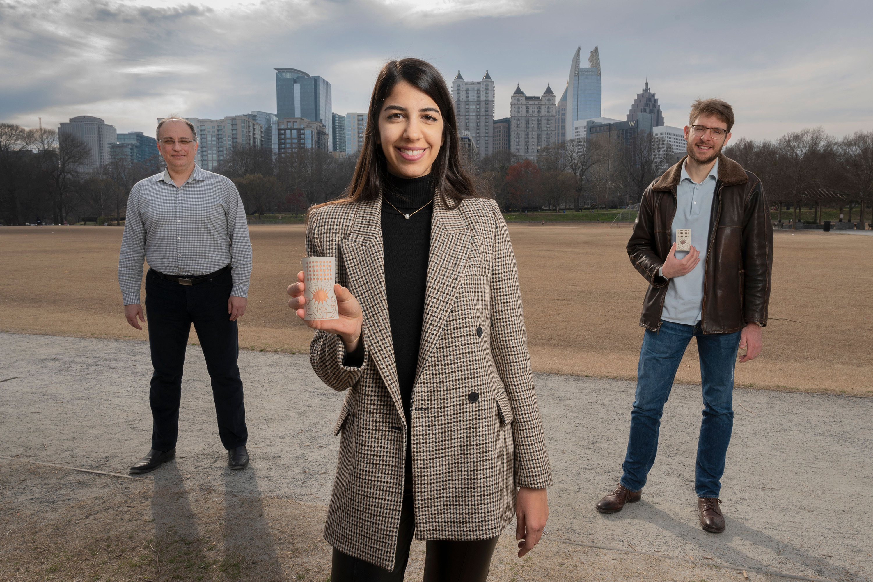 Georgia Tech researchers Aline Eid (center), Manos Tentzeris (left), and Jimmy Hester (right) have developed a flexible Rotman lens-based rectifying antenna system for 5G energy harvesting that could eliminate the world’s reliance on batteries for powering devices. (Photo credit: Christopher Moore, Georgia Tech) 


 