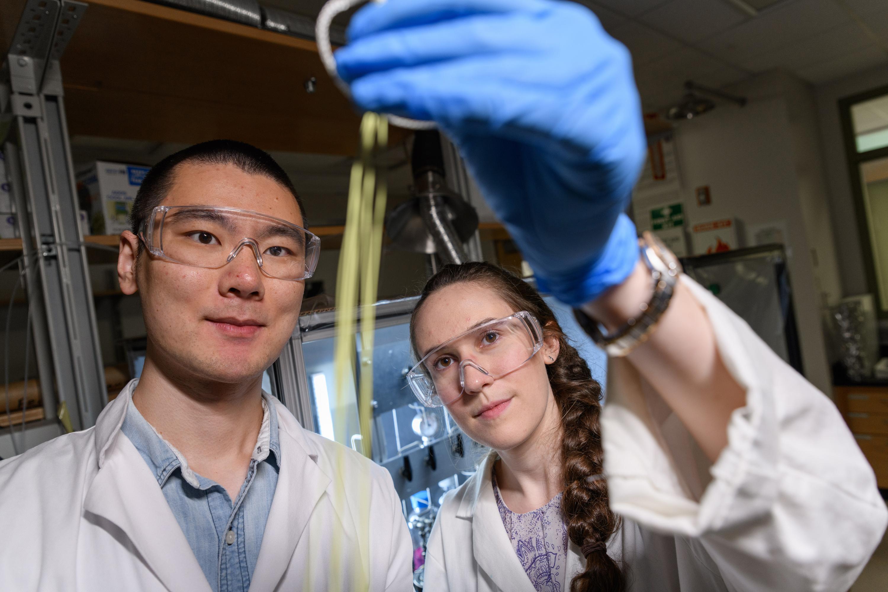 Fengyi Zhang and Emily K. McGuinness, graduate students at Georgia Tech, inspect a hollow fiber membrane that can be used for low-energy chemical separation. (Credit: Rob Felt)