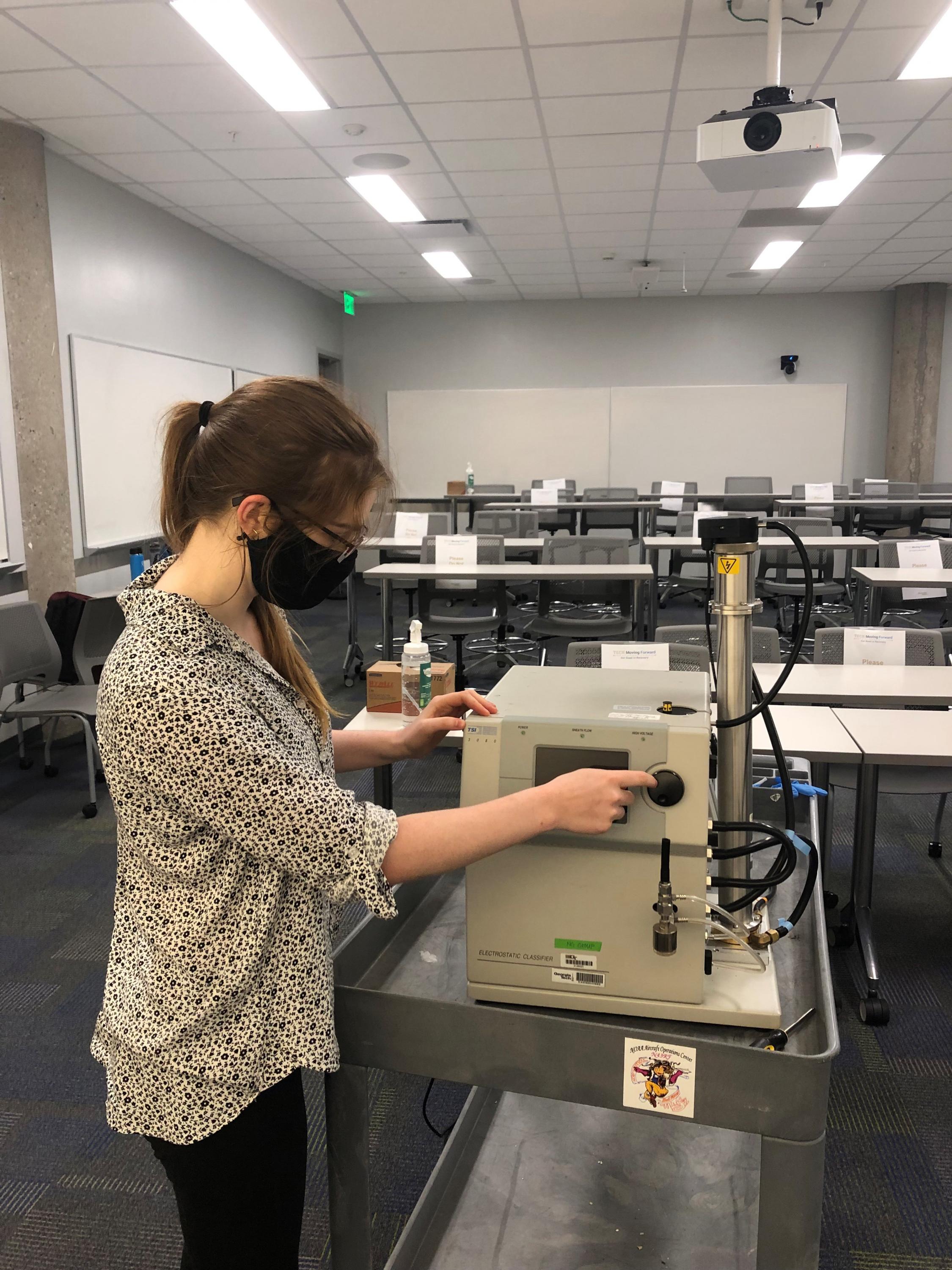 Graduate student Sabrina Westgate measures particle concentration in a classroom.