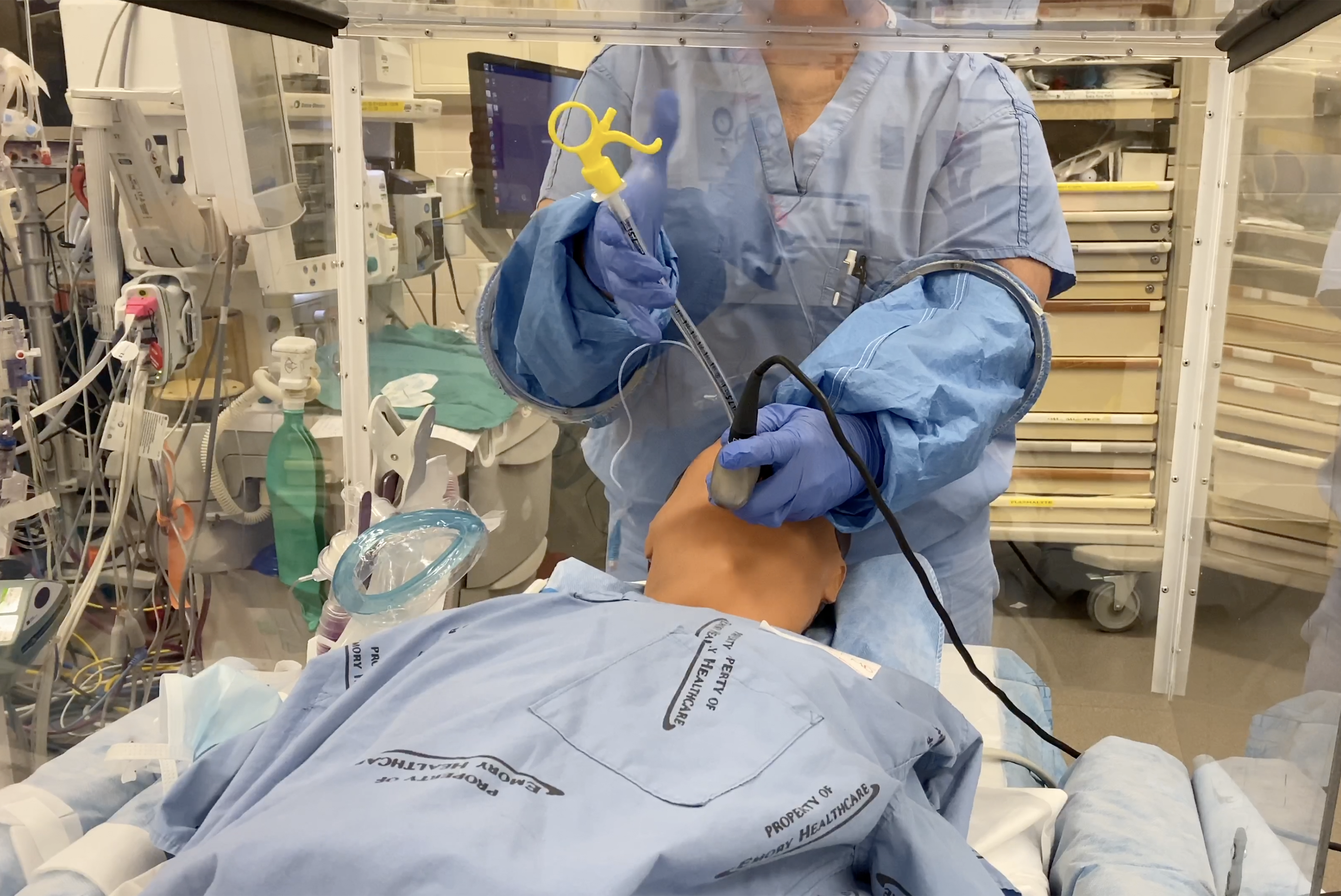 A clinician demonstrates how a barrier protection device allows procedures to be done while providing protection against aerosols from a COVID-19 patient. (Credit: Emory Healthcare)