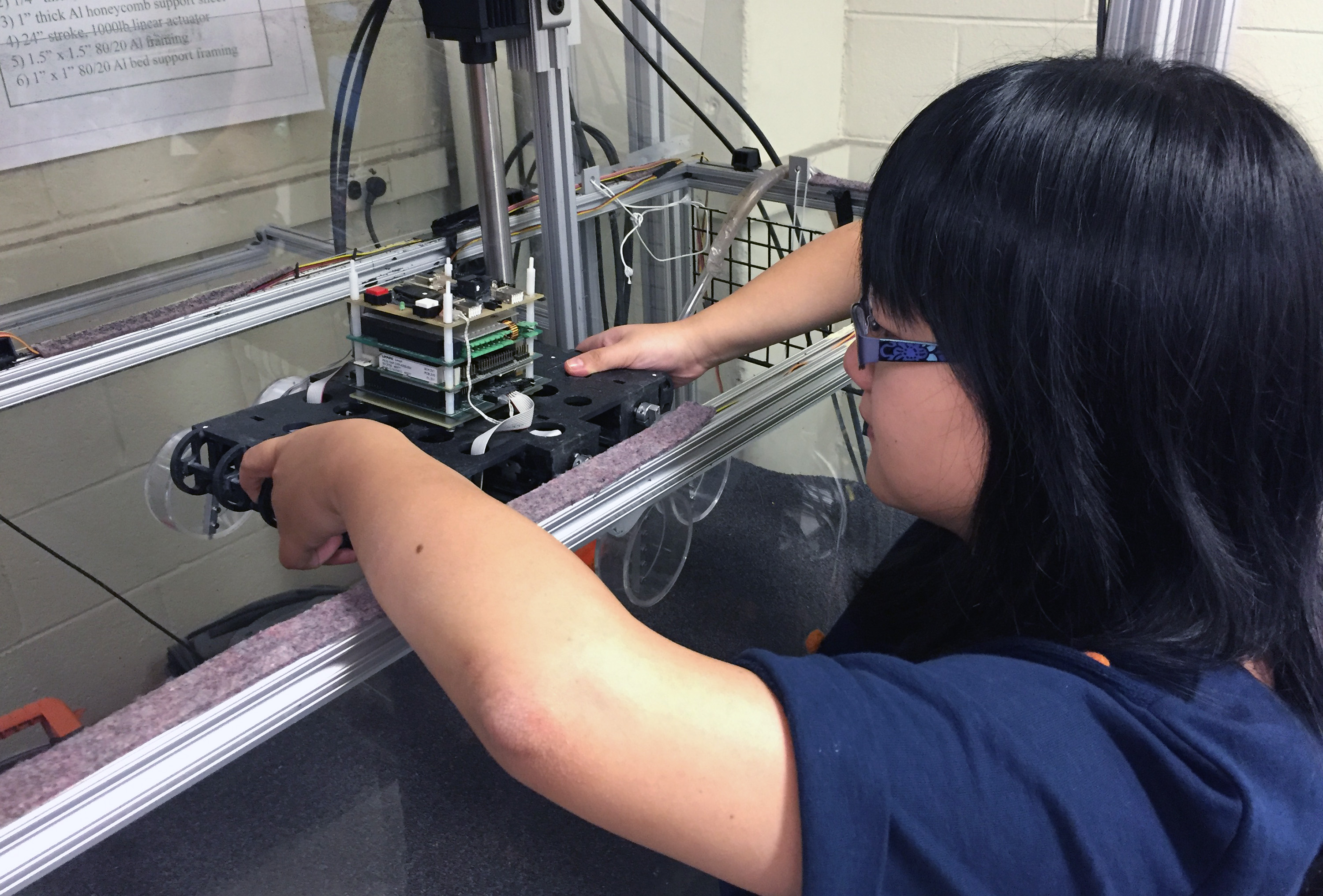 Georgia Tech graduate student Feifei Qian prepares to place Sandbot, a bio-inspired hexapedal robot, into a trackway filled with granular media. The robot was used to study how the stiffness of a loosely-packed surface affects the ability to move across it. (Credit: John Toon, Georgia Tech)