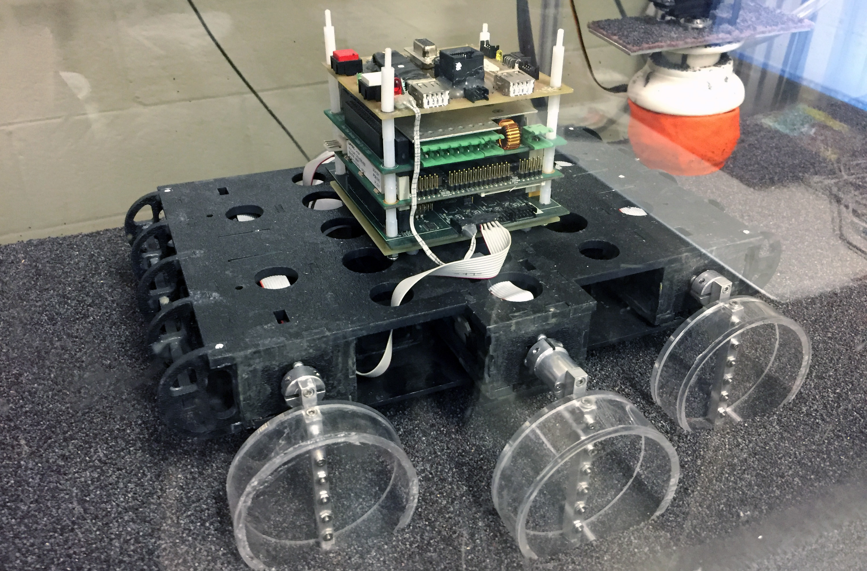 Sandbot, a bio-inspired hexapedal robot, is shown in a trackway filled with poppy seeds to simulate various granular surfaces. The robot was used to study how the stiffness of a loosely-packed surface affects the ability to move across it. (Credit: John Toon, Georgia Tech)