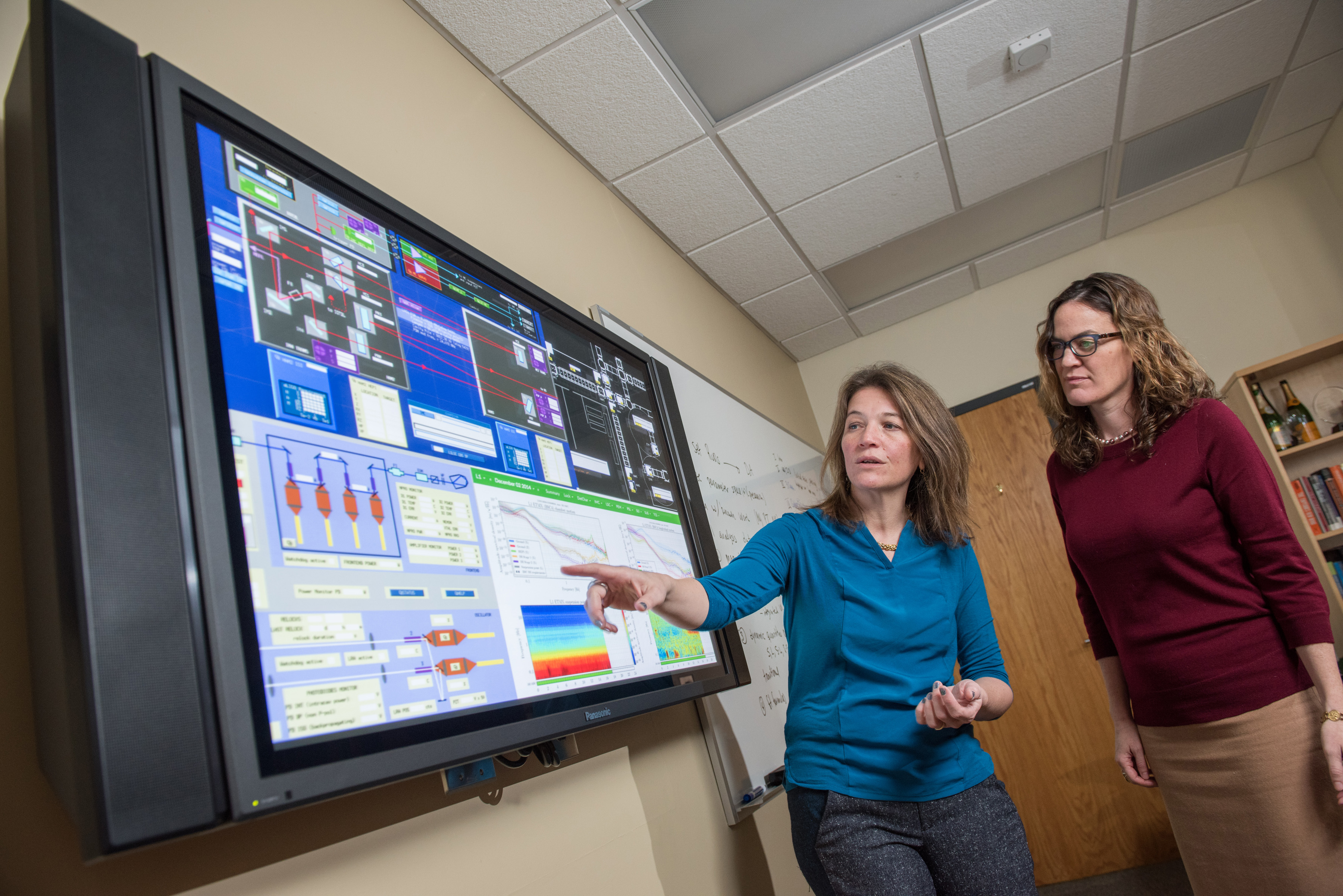 Laura Cadonati (left) and Deirdre Shoemaker discuss data monitoring tools that will be used to display live feeds from LIGO observatories. (Credit: Rob Felt)
