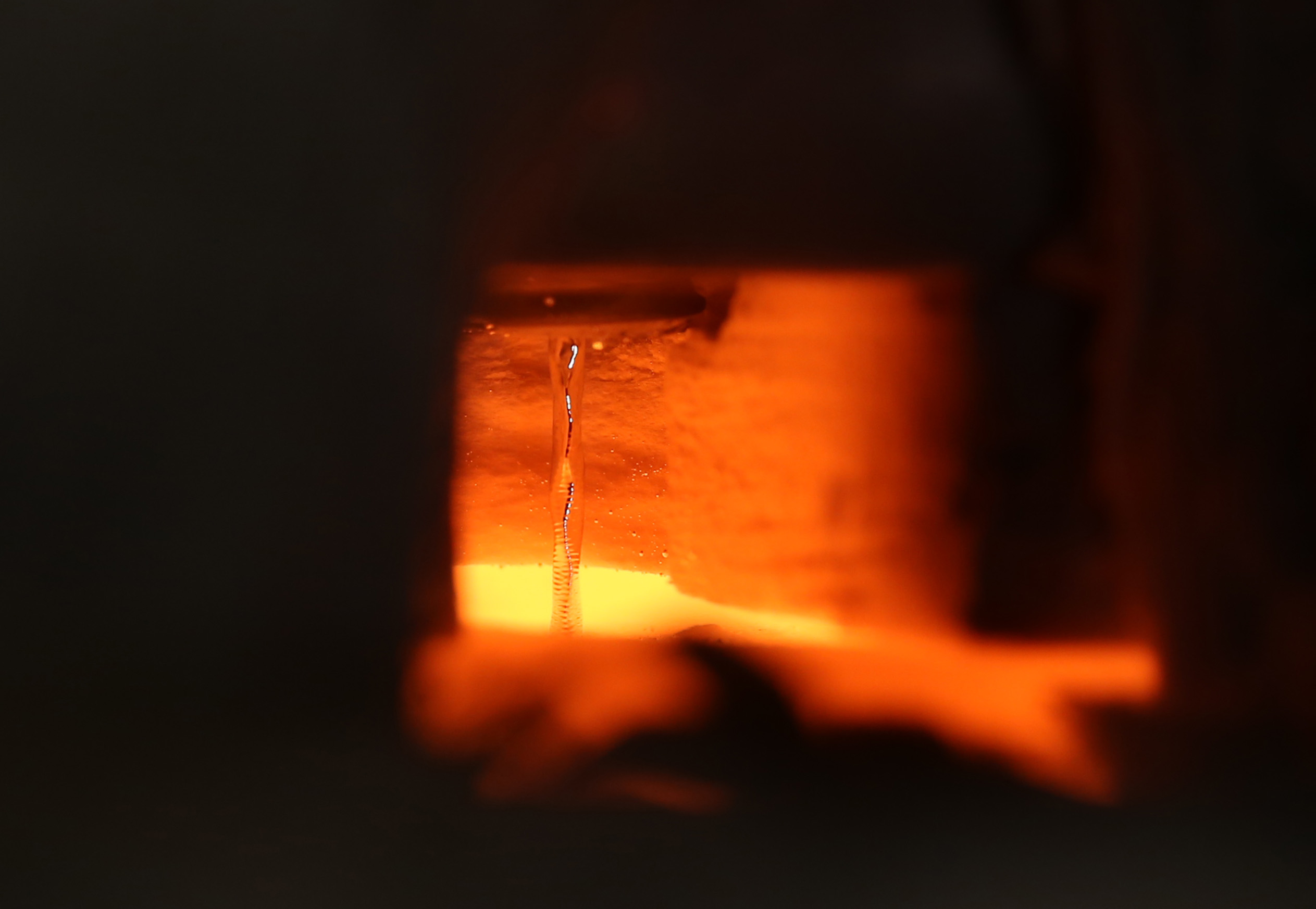 This image shows liquid metal flowing at 1400 degrees Celsius in the laboratory of Asegun Henry at Georgia Tech. Even though all the surrounding materials are glowing, the tin remains reflective and the ripples from the pool of tin below are visible via reflections from the stream. (Credit: Caleb Amy)