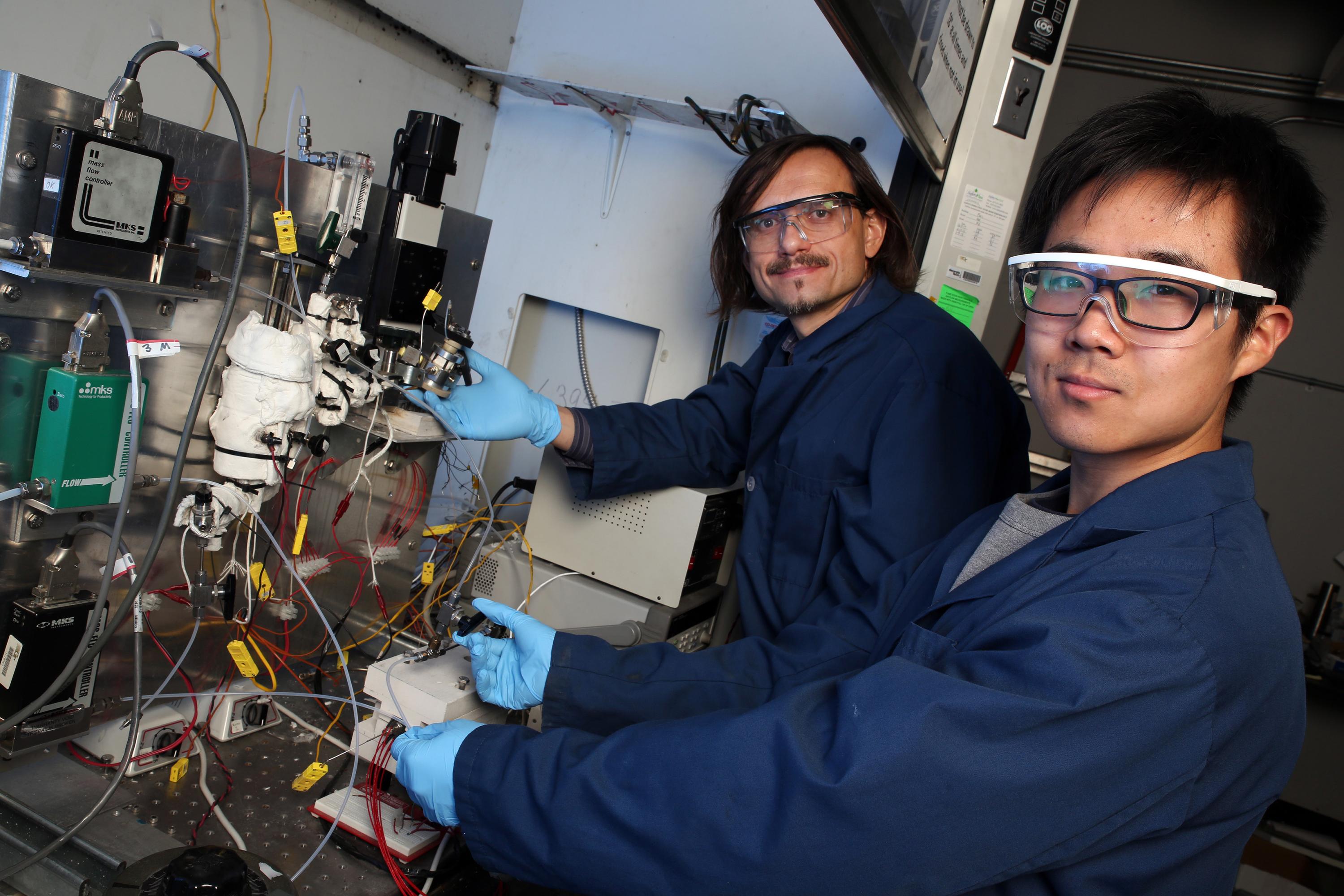 Georgia Tech professor Andrei Fedorov (left) and undergraduate research assistant Yuzhe Peng are shown with the laboratory-scale hydrogen reforming system that produces the green fuel at relatively low temperature in a process that can be scaled up or down to meet specific needs. (Credit: Candler Hobbs, Georgia Tech)