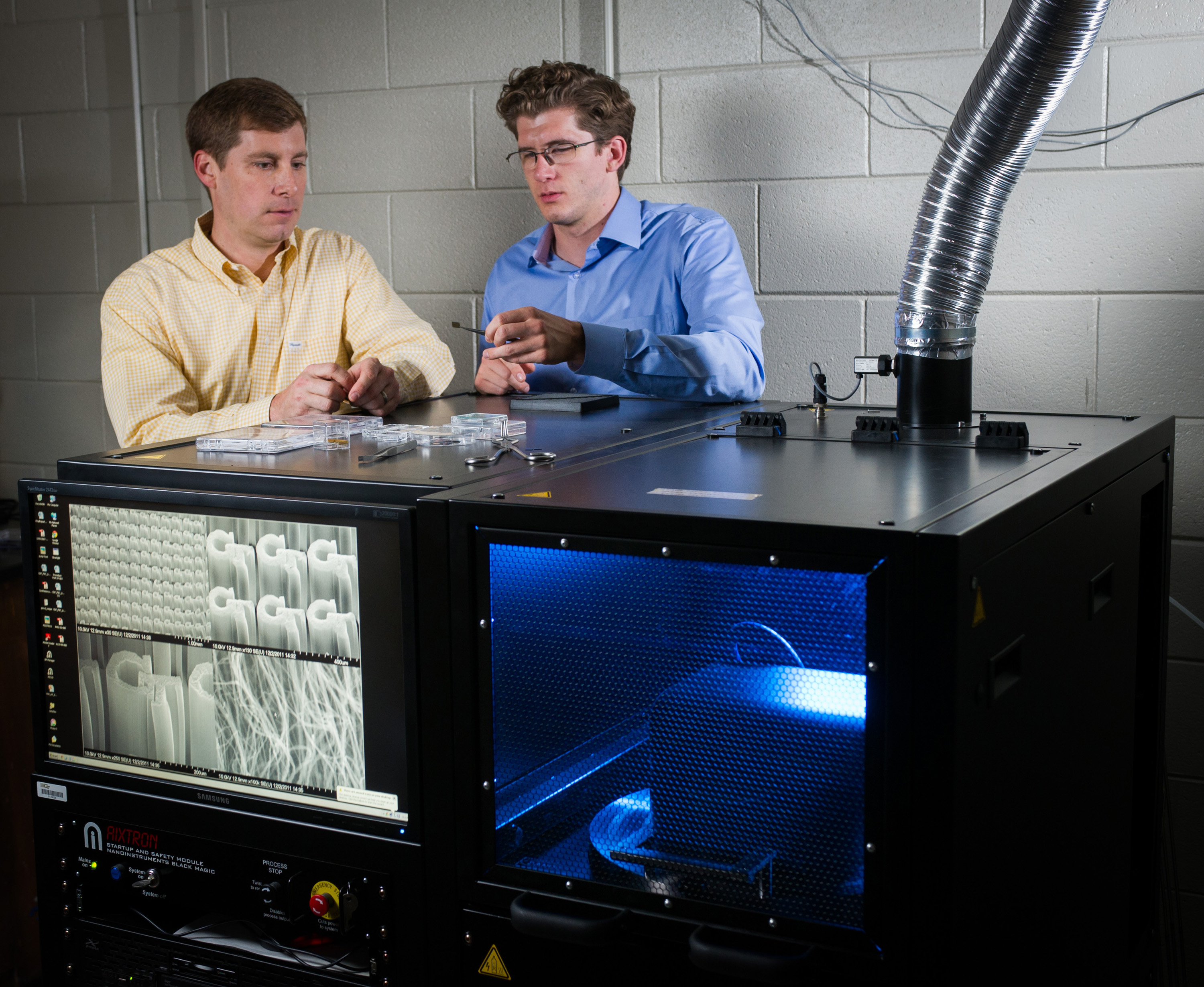 Georgia Tech researchers Jud Ready (left) and Graham Sanborn pose with equipment used to grow carbon nanotubes at the Georgia Tech Research Institute (GTRI) in Atlanta. The nanotubes are being tested for potential use in future electrically-powered ion propulsion systems. (Georgia Tech Photo: Rob Felt)