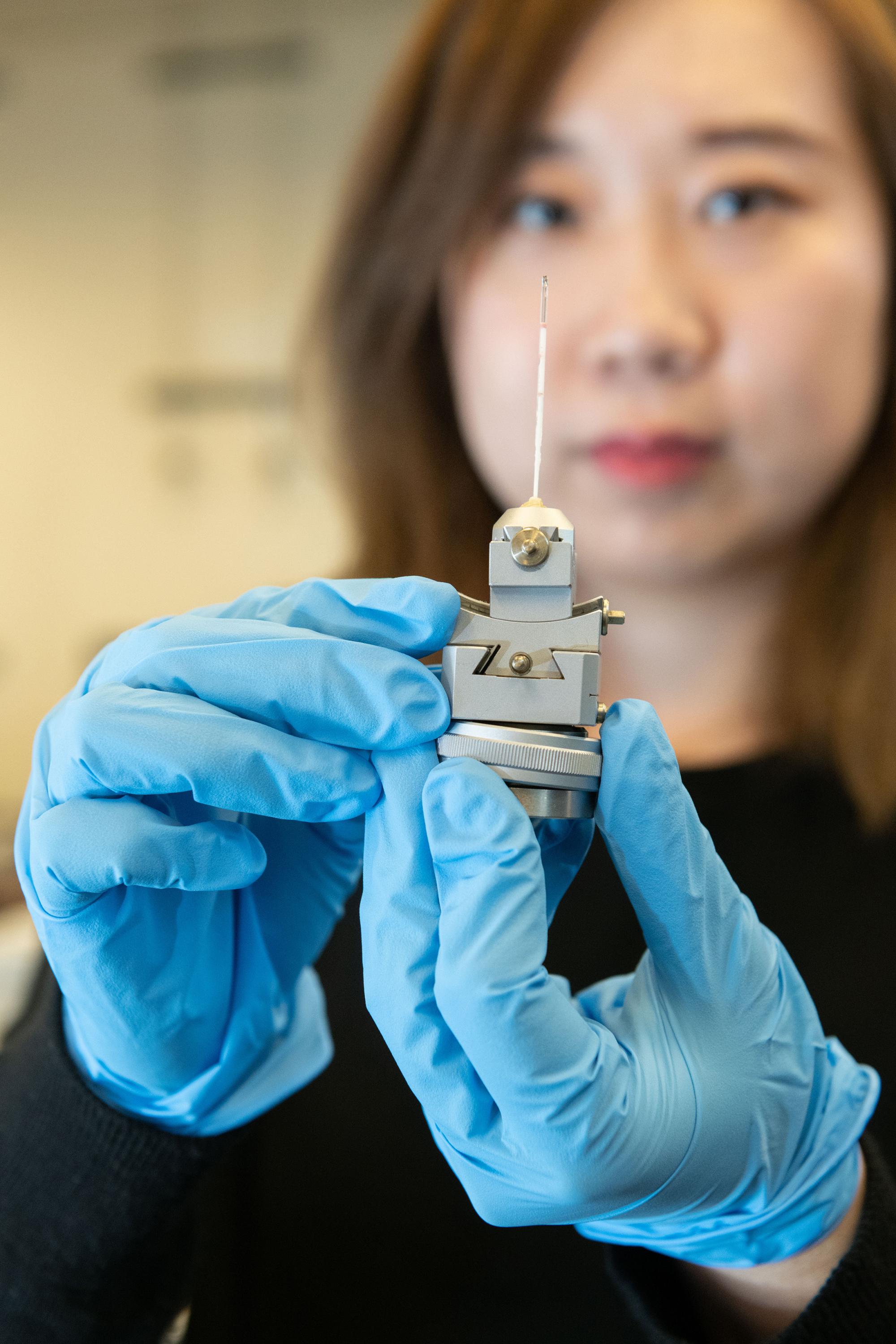 Georgia Tech graduate research assistant Xuetian Ma holds a reaction vessel similar to those used in the research on nanoscale crystalline growth. The vessels were made of a high-strength quartz tube about a millimeter in diameter and about two inches long. (Credit: Allison Carter, Georgia Tech)