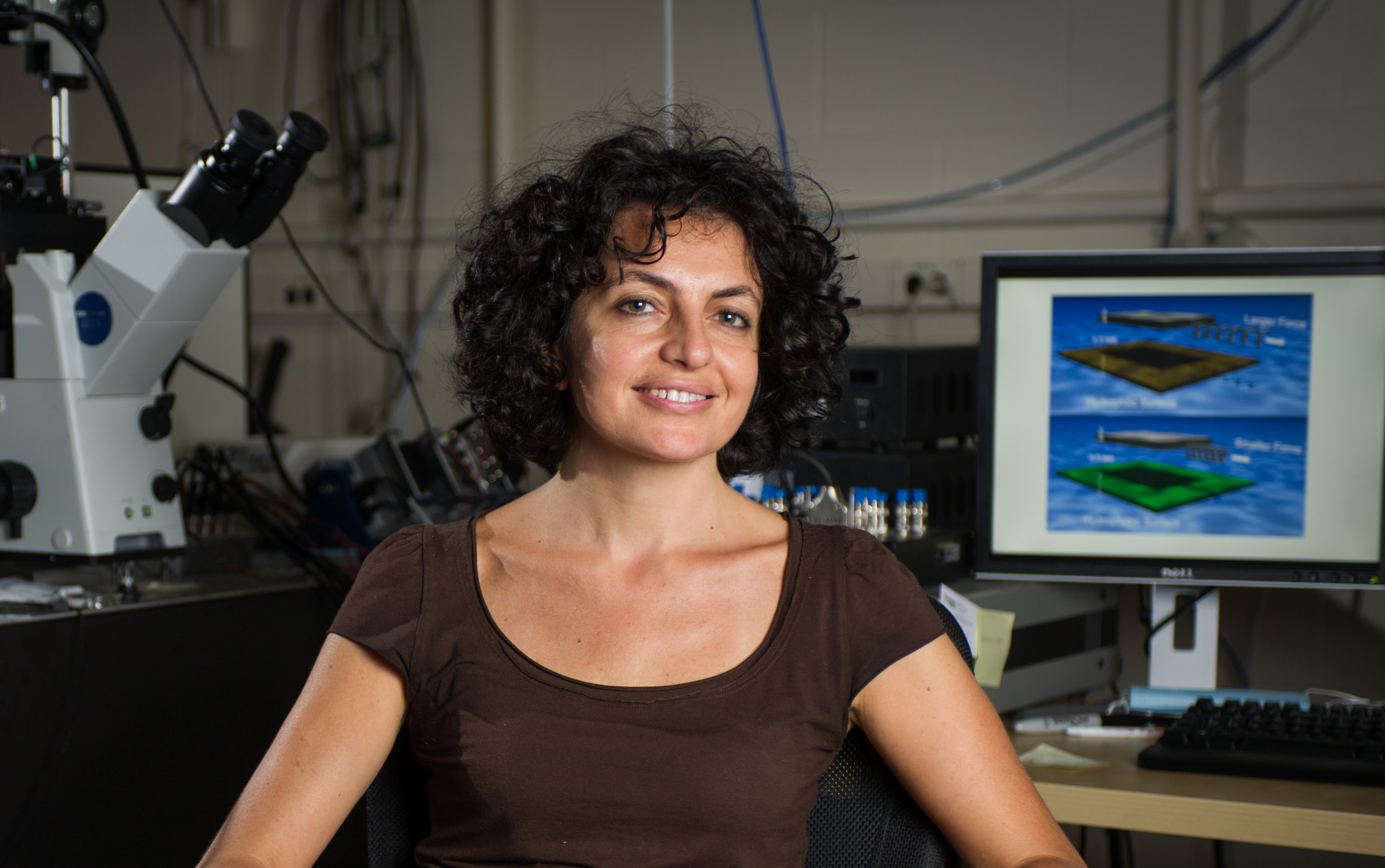 Georgia Tech School of Physics associate professor Elisa Riedo poses with instrumentation used to study how the properties of confining materials affect the effective viscosity of water at nanometer size scales. (Georgia Tech Photo: Rob Felt)