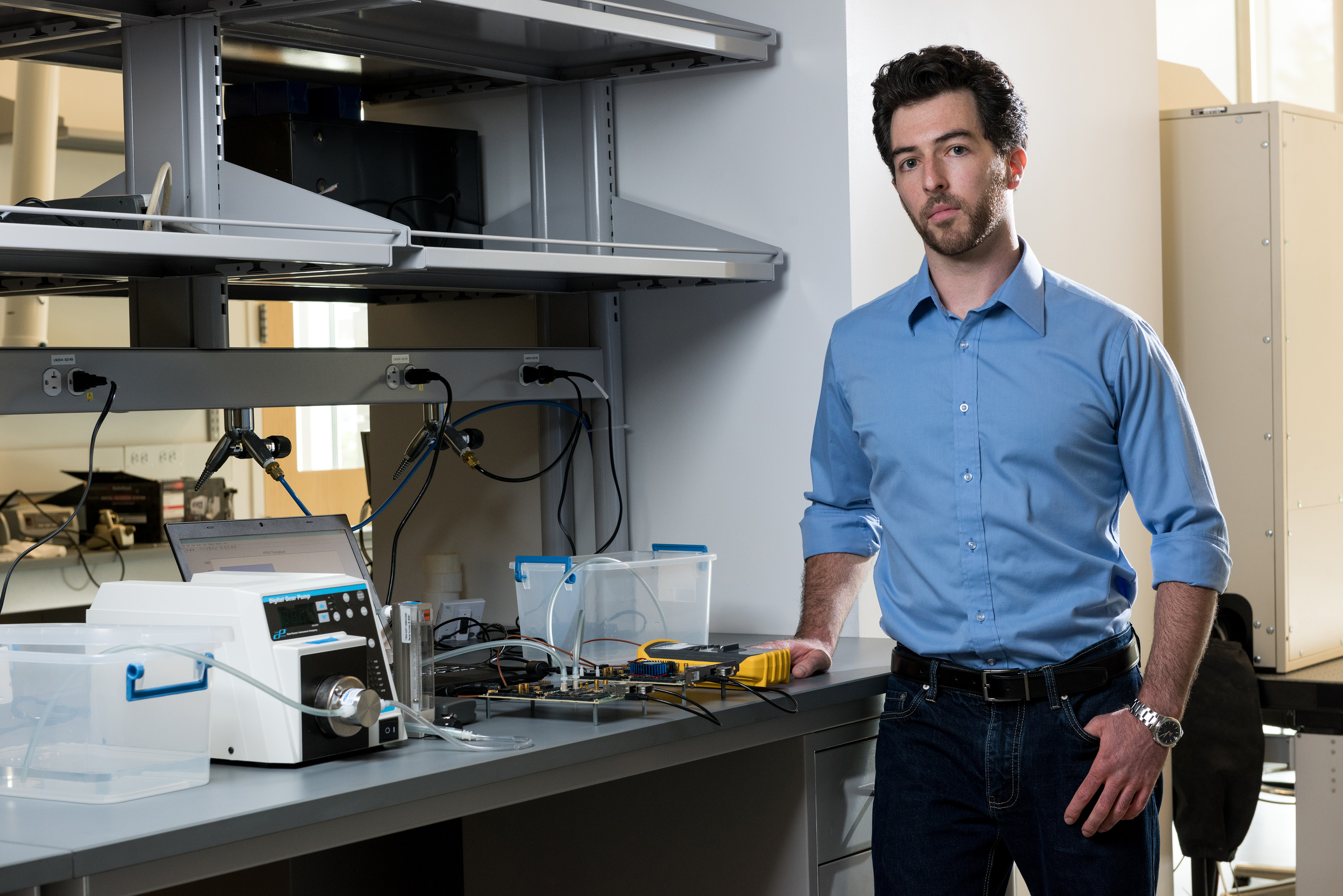 Georgia Tech graduate student Tom Sarvey is shown with test equipment used to compare the performance of stock FPGA devices, one with experimental liquid cooling and the other using stock air cooling. (Credit: Rob Felt, Georgia Tech)