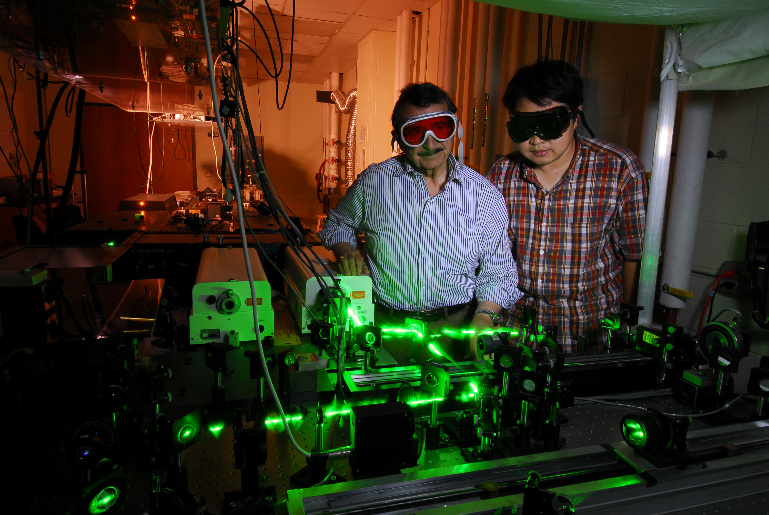 Mostafa El-Sayed (left) and Wei Qian shine laser light on cells with gold attached, allowing selective destruction of cancer cells. (Click image for high-resolution version. Credit: Gary Meek)