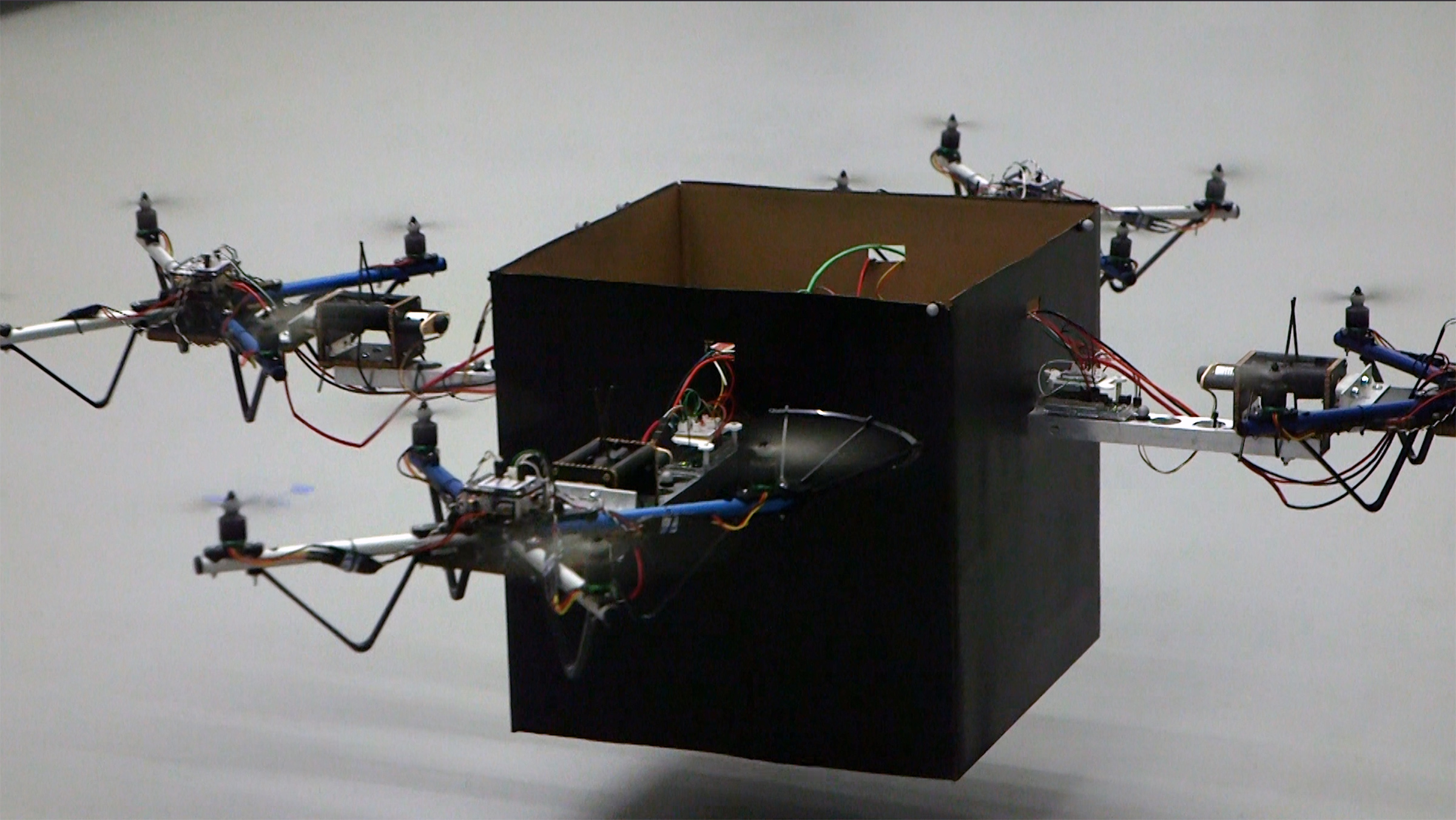 Four small drones work together to lift a package. An adaptive control algorithm could allow a wide range of packages to be delivered using a combination of several standard-sized vehicles. (Georgia Tech photo)