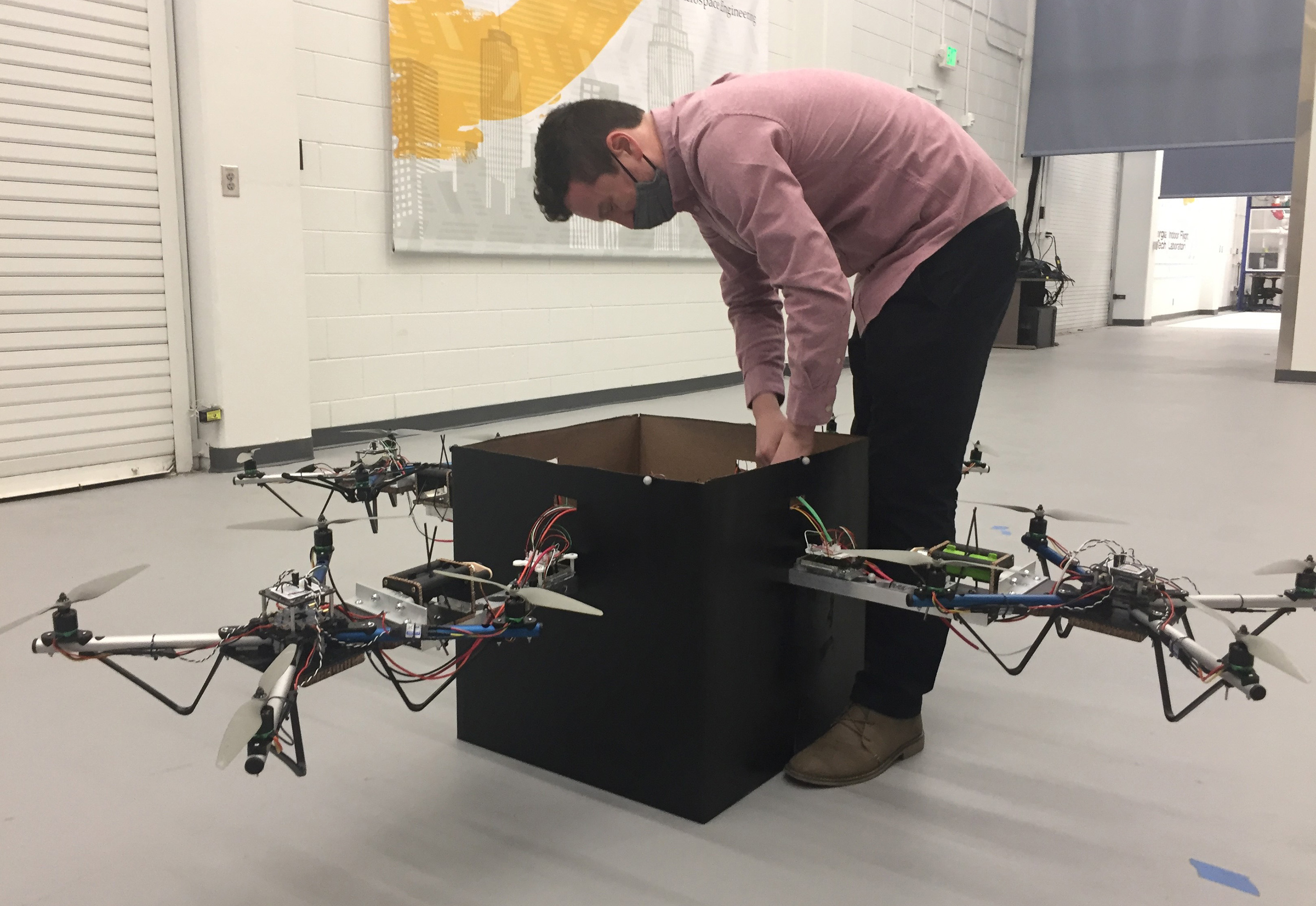Graduate student Kevin Webb adjusts the control system used to coordinate the activity of four drones to lift the package. (Credit: John Toon, Georgia Tech)